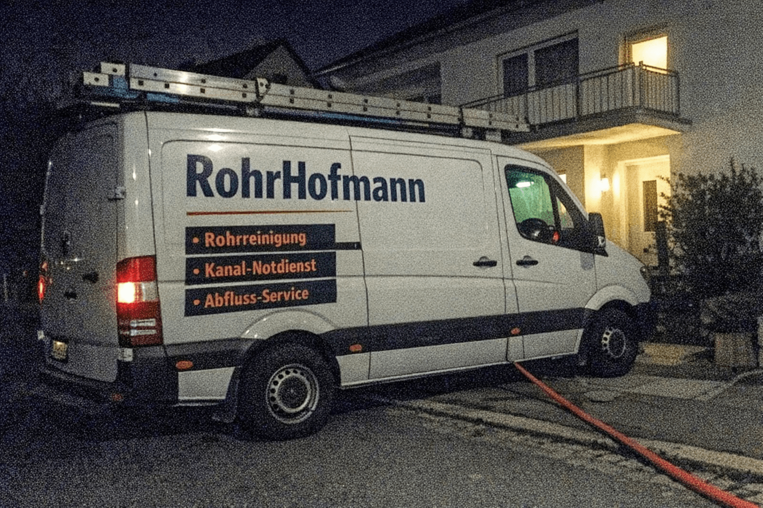 Servicefahrzeug bei Nacht vor einem Wohnhaus, Techniker bringt Ausrüstung zur Kellertür